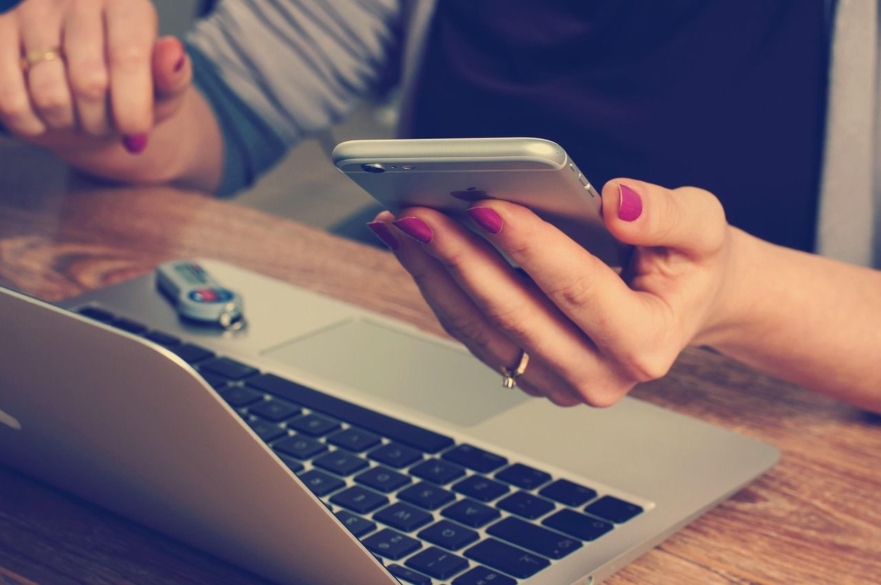 A person checking information on a phone next to an open laptop