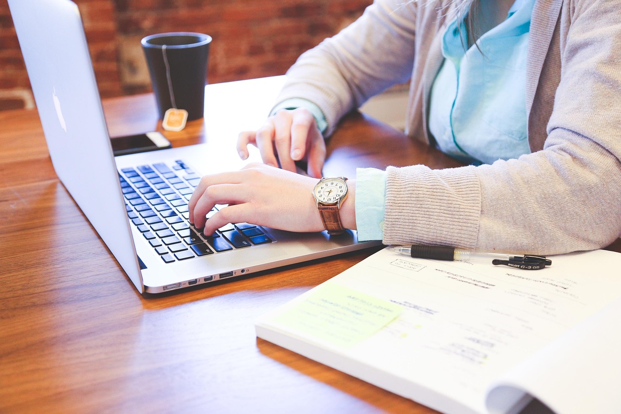 A woman working through an application on a laptop with annotated paperwork beside her